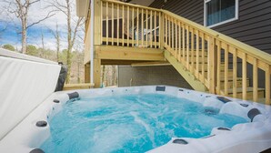 Ein Whirlpool auf einer Holzterrasse mit einer Holztreppe zu einem weiteren Terrassenbereich.
