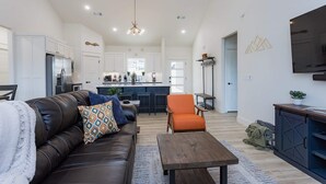 Ein großzügiges Wohnzimmer mit einer Ledersofa, einem Holztisch und einer Küche im Hintergrund.