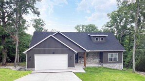 Ein zweistöckiges Haus mit Garage, einer Veranda und einem Steinfundament.