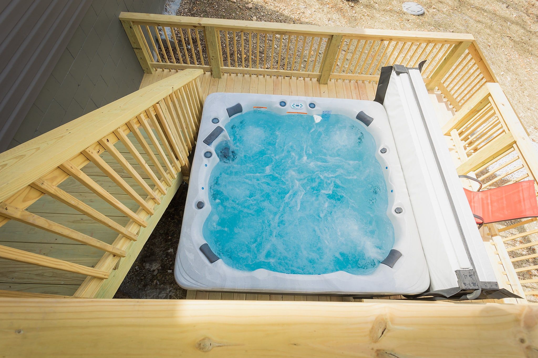 Un bain à remous doté d’une terrasse en bois et de garde-corps.