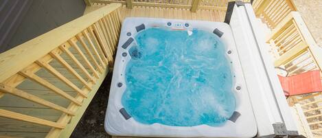 Un bain à remous doté d’une terrasse en bois et de garde-corps.