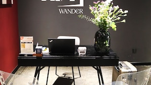 A reception desk with a laptop, a vase with flowers, and a sign that reads "KIN WANDER". - Kin Wander Tan Binh, The Mountain (Ho Chi Minh City)