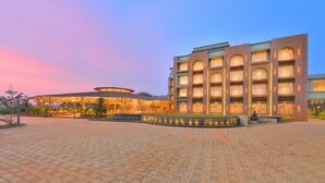 A hotel with a spacious courtyard, a covered outdoor seating area, and a building with multiple balconies. - URBANE BY TREAT  (Daman)