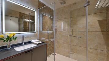 Un baño moderno con cabina de ducha de vidrio, tocador con lavabo y espejo.