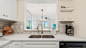 A kitchen with a large window, a built-in sink, and a coffee maker. - Oceanfront Resort 2BR Condo – Poolside, Scenic Pond Views, Sleeps 6 (St. Augustine)