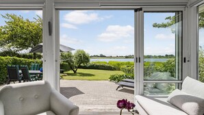 A conservatory with a view of a lake and greenery. - 2 bedroom nice home in Kerteminde (Kerteminde)