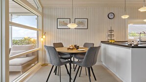 A modern kitchen with a round dining table, grey chairs, pendant lights, and a view of the outdoors. - 2 bedroom nice home in Kerteminde (Kerteminde)