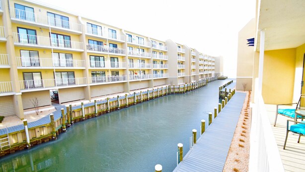 A multi-story hotel with balconies, a waterway in front, and a dock extending into the water. - Wight Bay 223-Baywater 47th St, Pool, Elev, W/D, AC, Free WIFI (Ocean City)