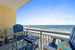 Un balcon avec deux fauteuils Adirondack, une petite table et une vue sur la plage et l’océan.
