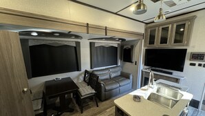 Ein kompaktes Wohnmobil-Interieur mit Küchenzeile, Sitzgruppe und Unterhaltungssystem.