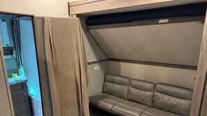 Ein kompakter Wohnbereich mit Schlafsofa, einer kleinen Küchenzeile und einer Dusche.