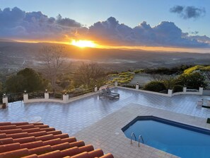 Une piscine sur le toit offrant une vue sur le coucher de soleil au-dessus d’une vallée.