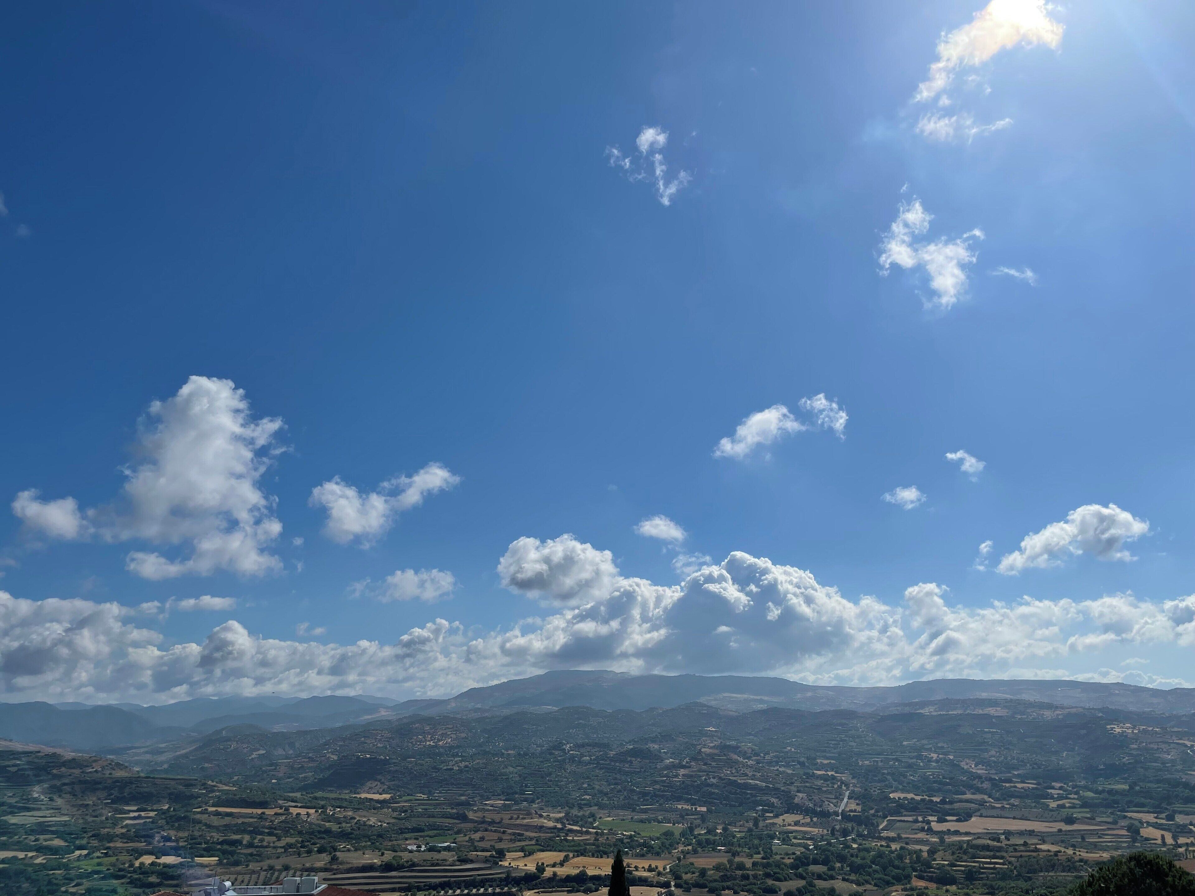 A panoramic view of a landscape with rolling hills and a clear sky.