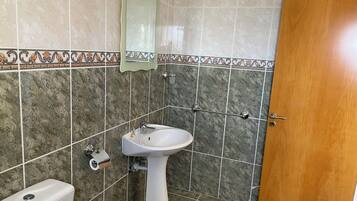 A bathroom with a white sink, a toilet, and a wooden door.