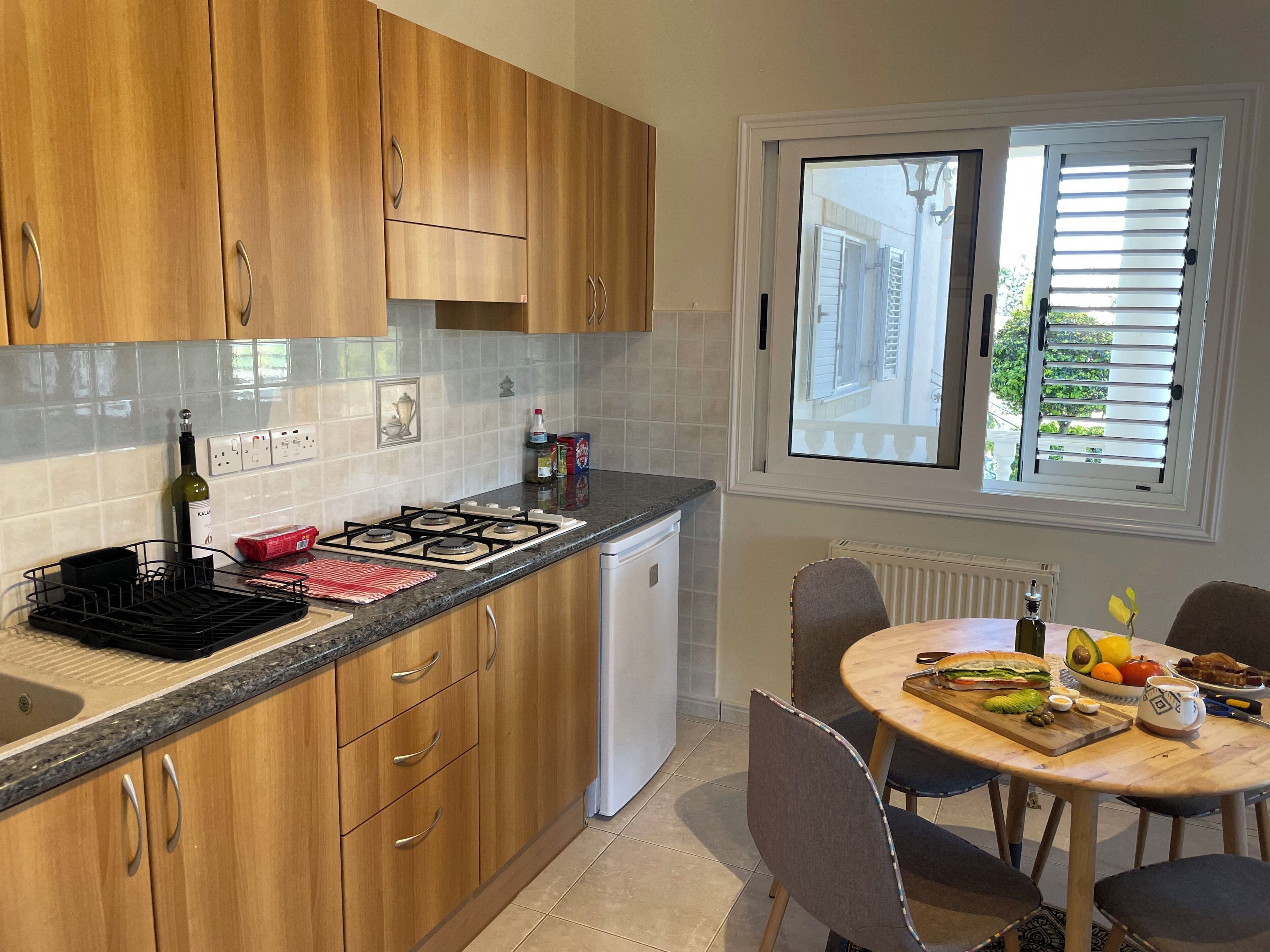 Una cocina moderna con armarios de madera, una estufa a gas y un comedor con una mesa lista para dos personas.