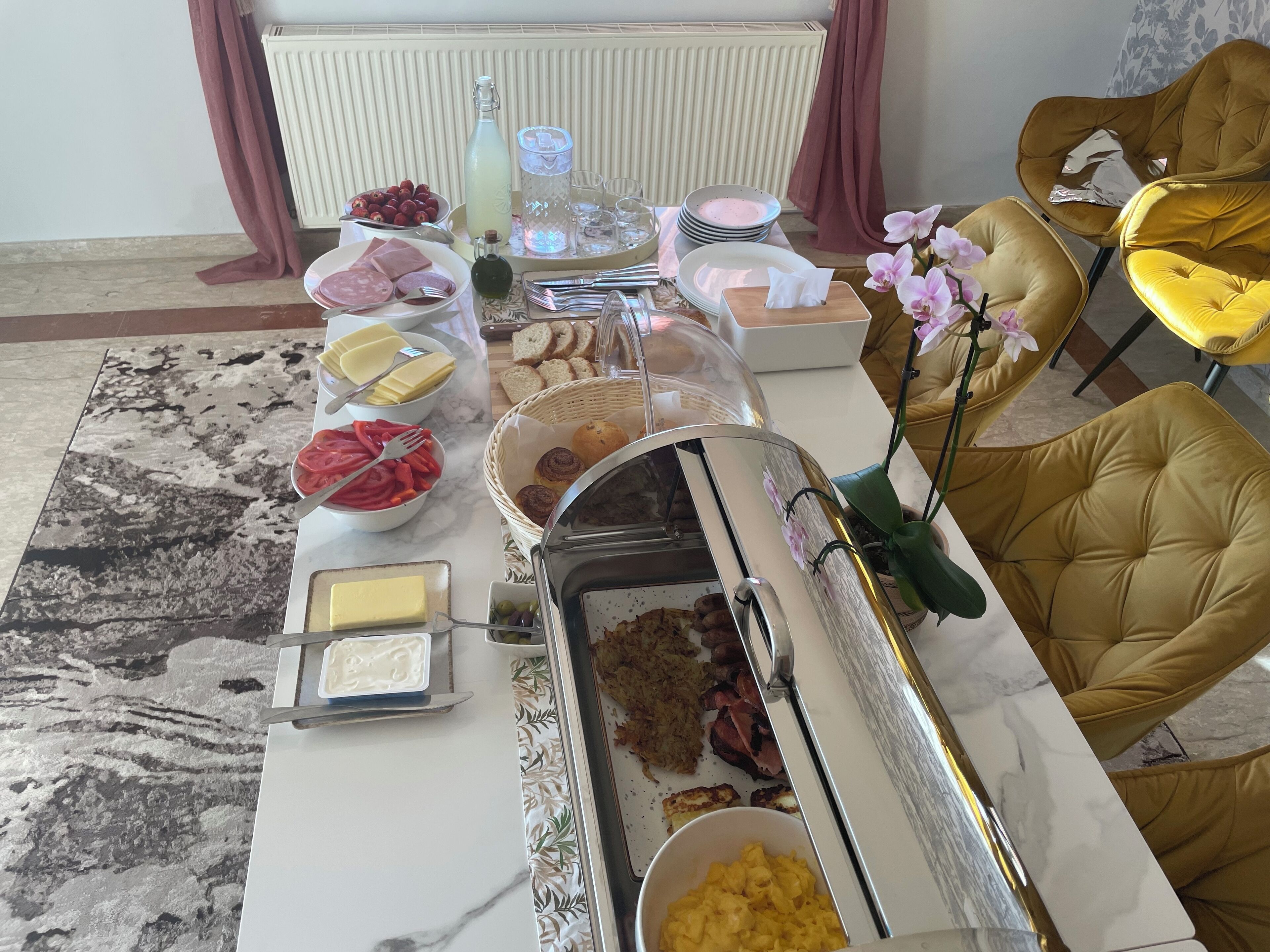 En frukostbuffé med ett varierat utbud av mat, serveringsredskap och en dryckesautomat.