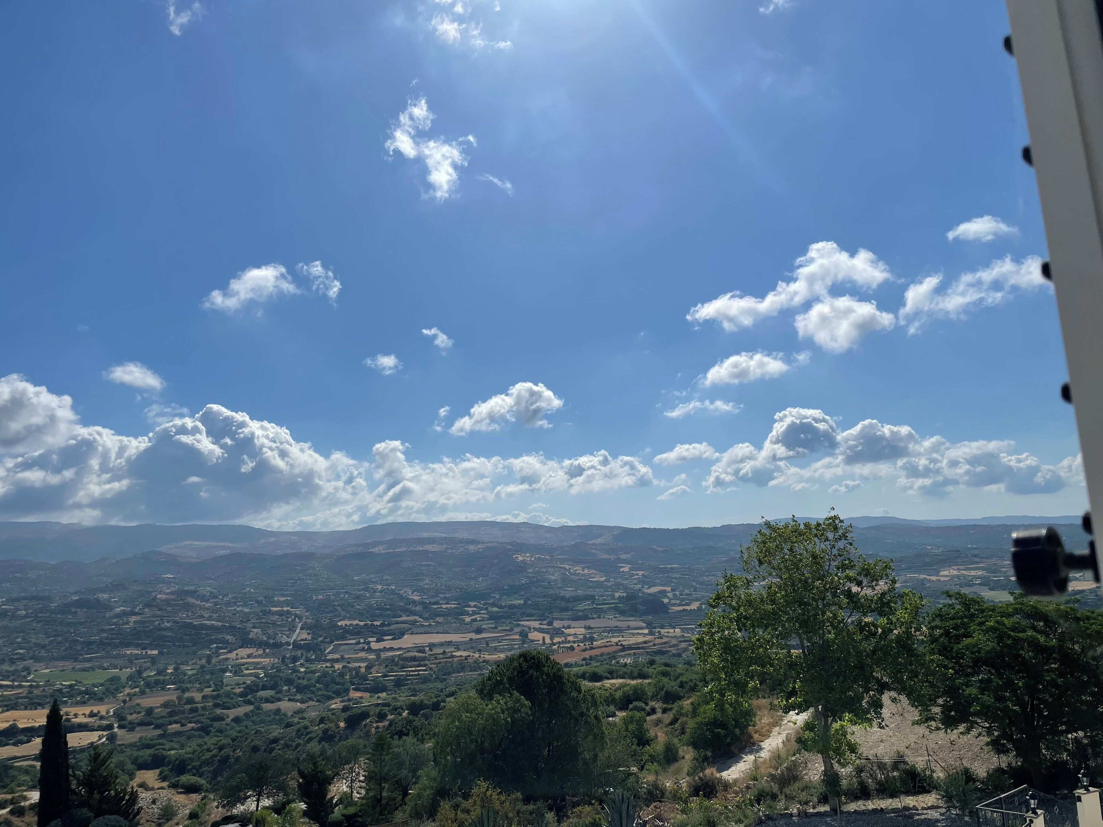 Une vue panoramique d’une vallée parsemée de nuages, avec des montagnes qui se dessinent à l’horizon.