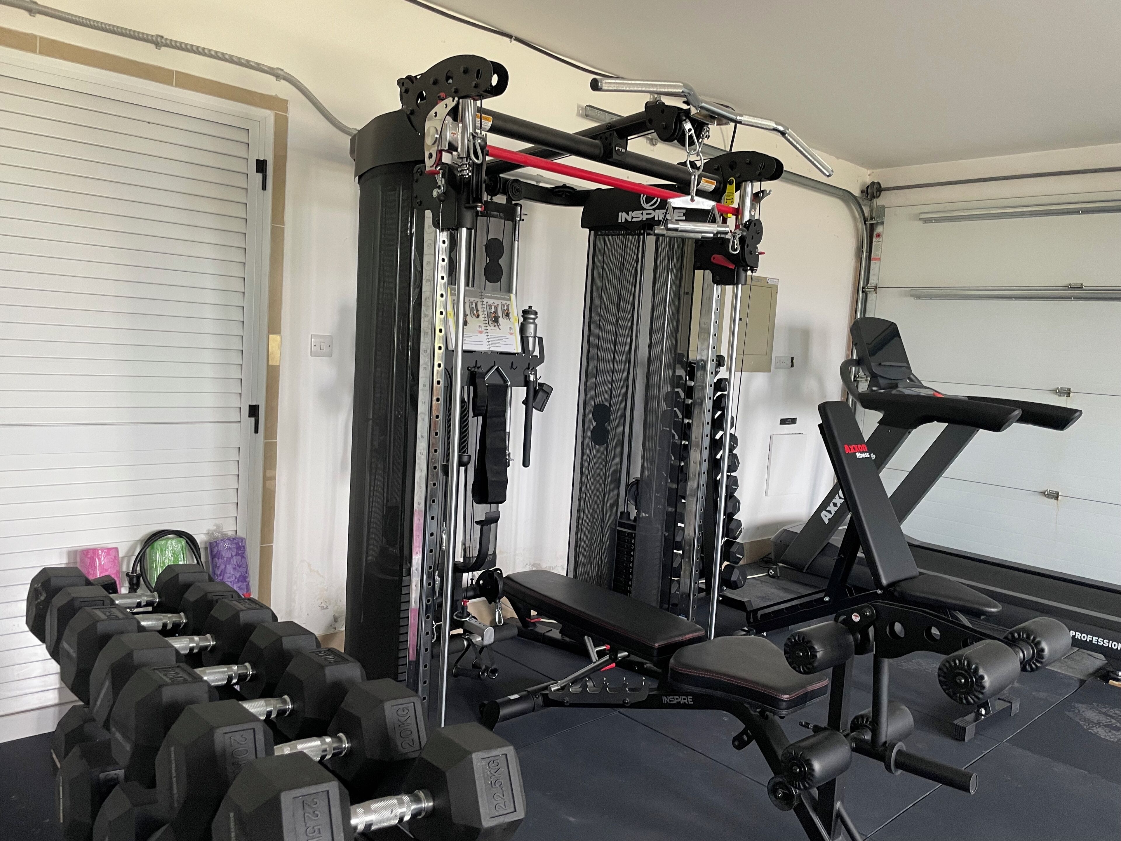 A home gym with a weight bench, dumbbells, and a cable machine.