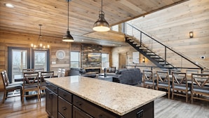 A spacious kitchen with a granite island, wooden ceiling, and a staircase leading to an upper level. - Treehouse Lodge 5 Bedroom Cabin by RedAwning (Sevierville)