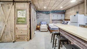 A rustic kitchen with a wooden countertop, bar stools, and a refrigerator. - Casas Coastal Experience Cabin B 1 Bedroom Cottage by RedAwning (Rockport)