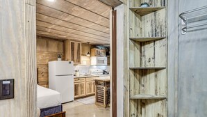 A compact kitchen with wooden cabinets, a white refrigerator, a microwave, and a sink. - Casas Coastal Experience Cabin B 1 Bedroom Cottage by RedAwning (Rockport)