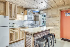 Una cocina con armarios de madera, microondas, fregadero y una isla grande con taburetes.