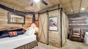 A bedroom with a bed, a chair, a lamp, and a poster on the wall.