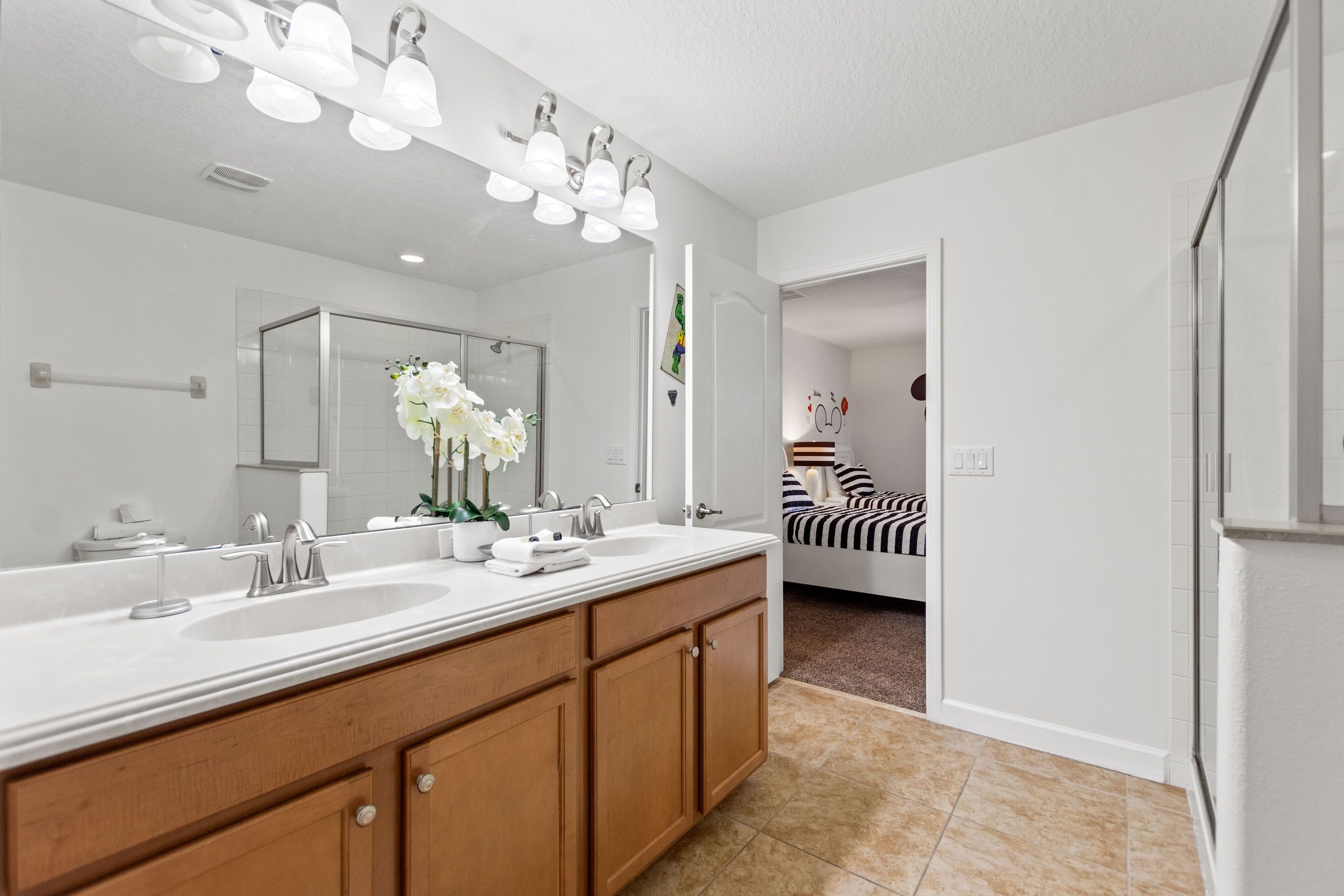 A bathroom with two sinks, a large mirror, and a shower.
