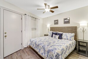 A bedroom with a bed, a ceiling fan, a nightstand, and a wall-mounted lamp. - Newly Renovated Villa! (Hilton Head Island)
