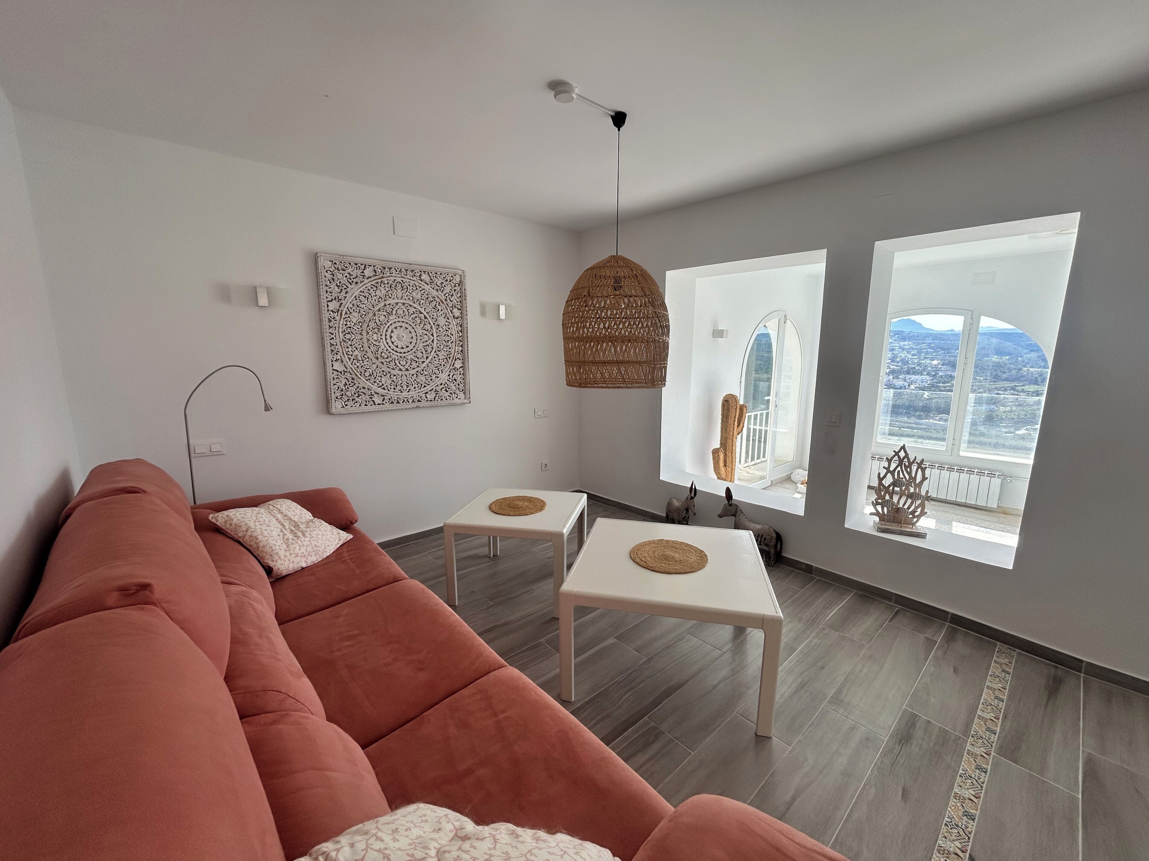 A modern living room with a sectional sofa, a small table, and a hanging light fixture.