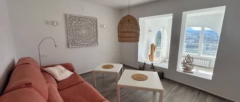 A modern living room with a sectional sofa, a small table, and a hanging light fixture.