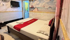 A hotel room with a bed, a desk with a phone, a fan, and a TV. - Gia Bao Hotel Binh Thanh - by BayLuxury (Ho Chi Minh City)
