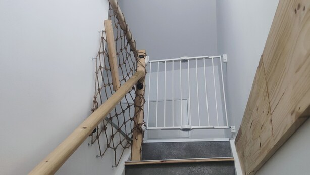 Eine Holztreppe mit einem Metallgitter oben.
