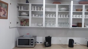 Eine Küche mit weißen Schränken, einer Mikrowelle, einer Kaffeemaschine und einem Toaster.