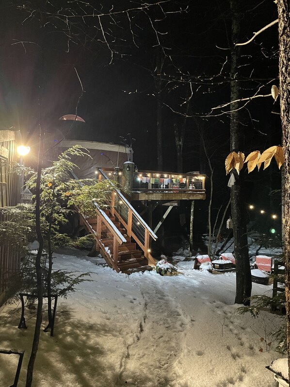 A snow-covered outdoor area with wooden stairs leading to a covered seating area.