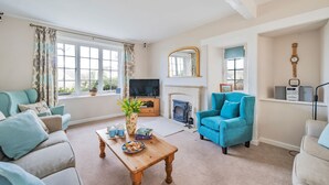 Una sala de estar con chimenea, televisor y un sillón azul.