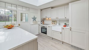 Una cocina moderna con armarios blancos, una isla grande y un tragaluz.