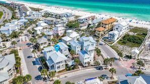 An aerial view of a coastal residential area with houses, a beach, and a clear blue sky. - Seas The Moments: Next to beach walkover, across the street from the pool! (Panama City Beach)