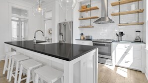 A modern kitchen with a central island, white cabinetry, stainless steel appliances, and pendant lighting. - Seas The Moments: Next to beach walkover, across the street from the pool! (Panama City Beach)