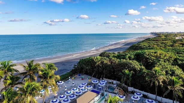 Un resort sulla spiaggia con area piscina, palme e vista sull'oceano.