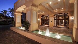 L'ingresso di un hotel con una fontana, una tettoia e un'entrata con porta in vetro.