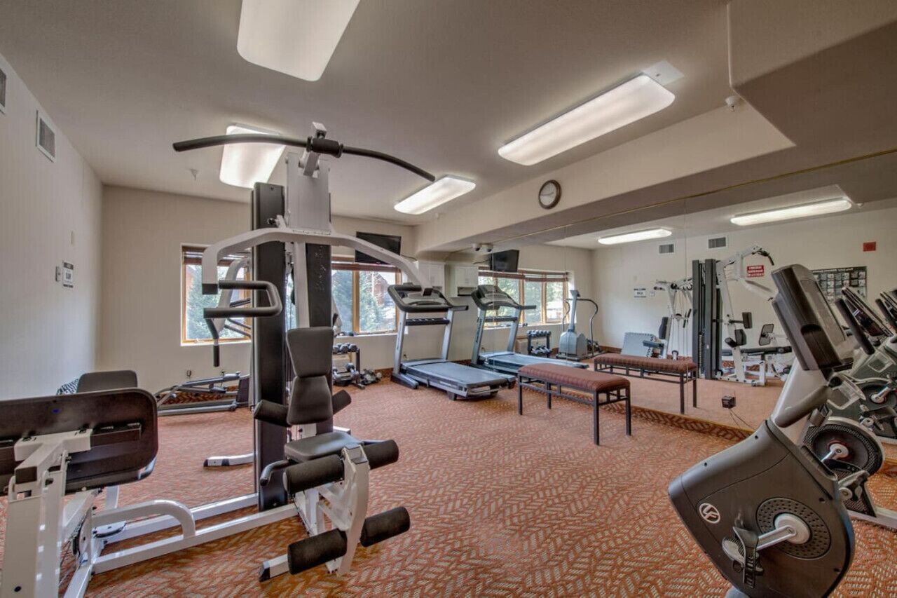 Une salle de sport équipée de divers appareils d’exercice, notamment des tapis de course, des appareils de musculation et un banc.