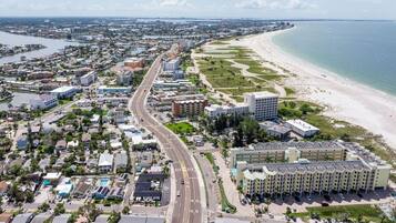 Une vue aérienne d’une ville côtière, avec une route principale bien visible, une plage et un grand hôtel à plusieurs étages, doté d’un parking.