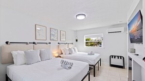 Hotelkamer met twee bedden, een raam met uitzicht, een flatscreen-tv en een plafondlamp.