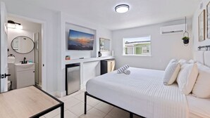 Une chambre d’hôtel moderne équipée d’un lit, d’un bureau, d’une salle de bain, d’une télévision et d’une fenêtre.