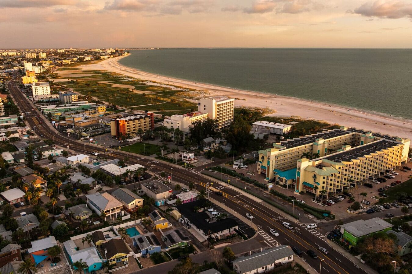 An aerial view of a coastal city with a beachfront hotel, roads, and residential areas.