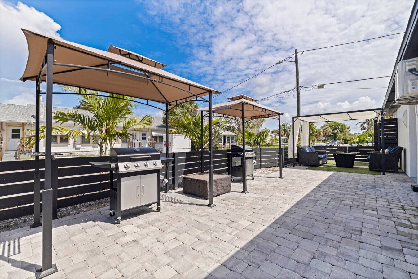 An outdoor patio with a barbecue grill, seating area, and umbrellas providing shade.