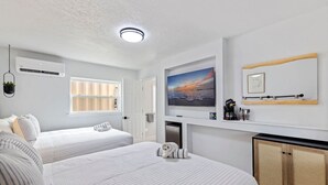 Une chambre d’hôtel avec deux lits, une télévision, une fenêtre, un luminaire au plafond et un placard.