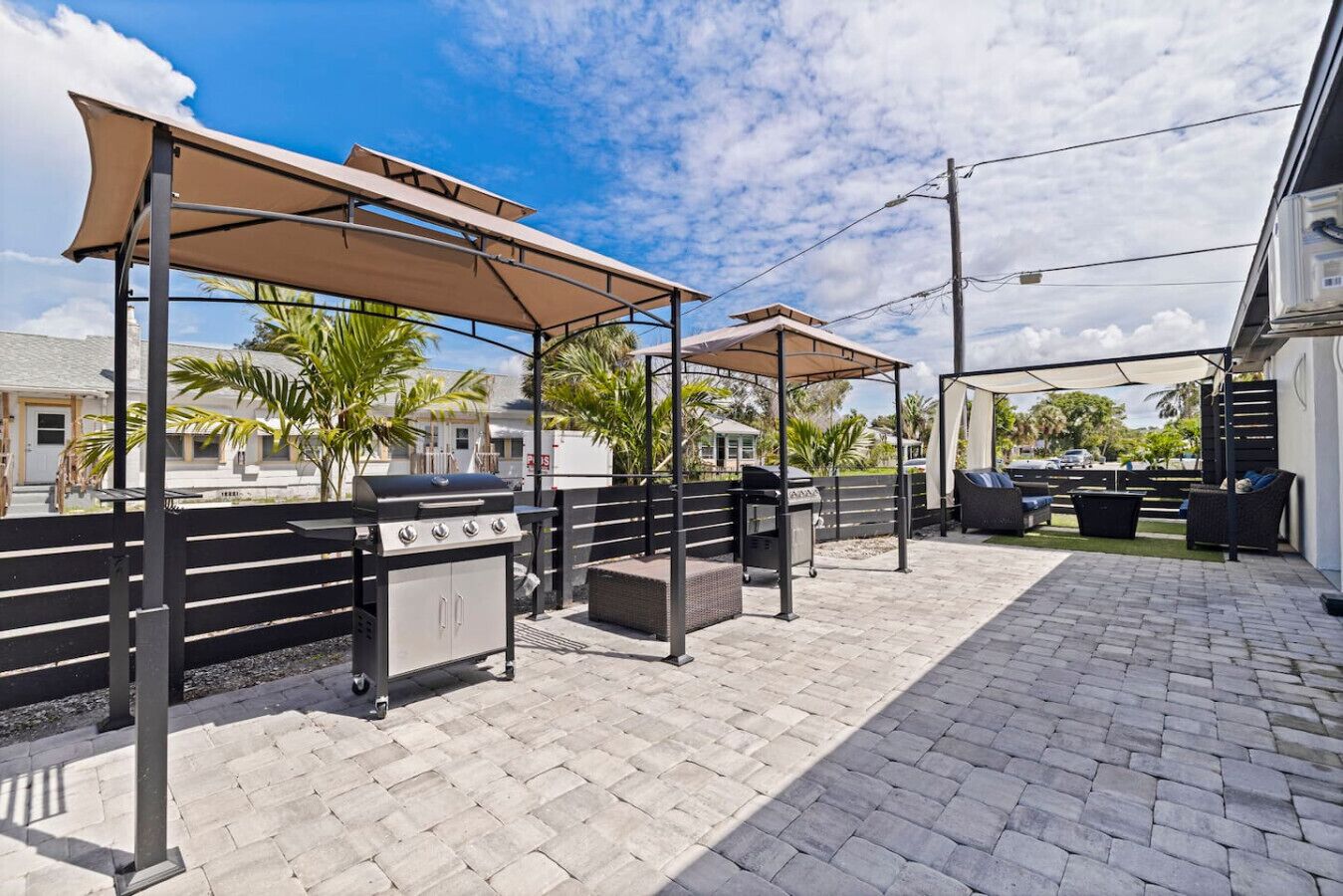 Eine Terrassengruppe mit Grill, Sitzgelegenheiten und Sonnenschirmen.