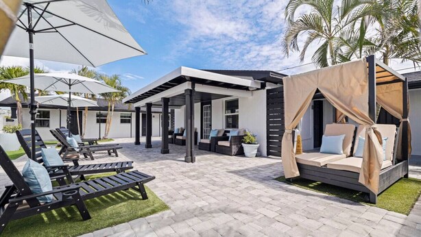 A modern outdoor lounge area with sun loungers, a covered seating area, and a canopy bed.